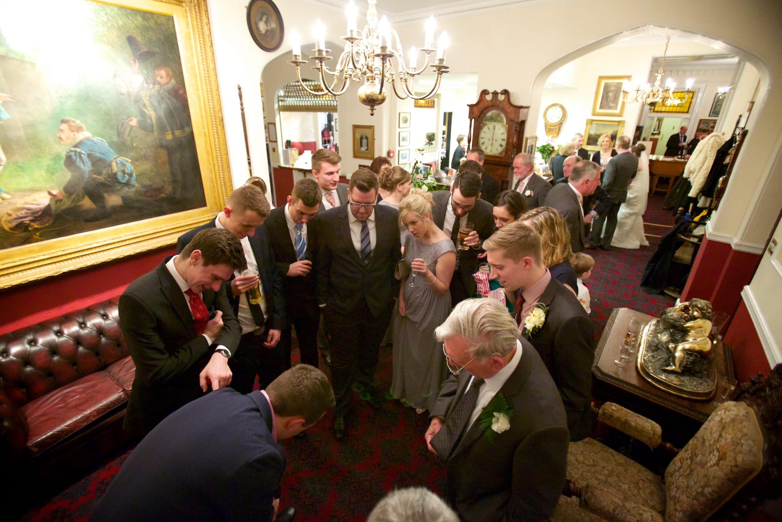 Guests gathered around Lewis in an elegant wedding venue interior.