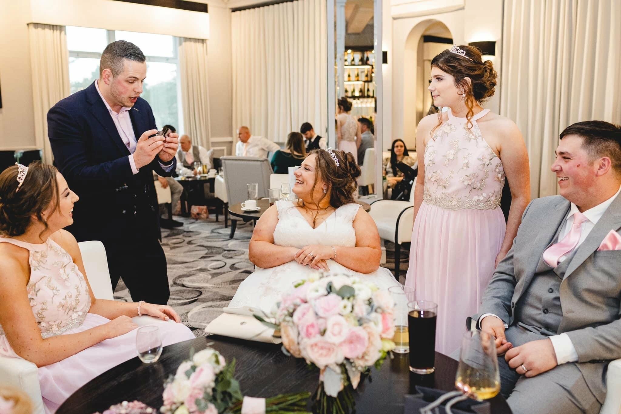 Lewis Belcher performing close-up magic for wedding guests at a table.
